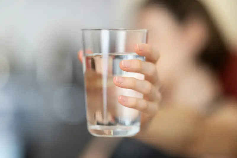 A hand holding a clear glass of water
