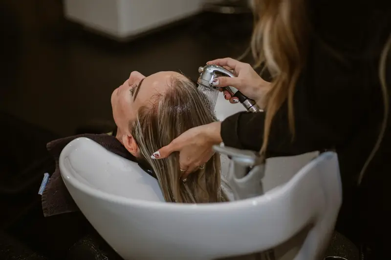 A hair stylist working on a woman’s hair in a salon