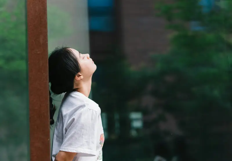 A woman outdoors looking up at the sky in daylight