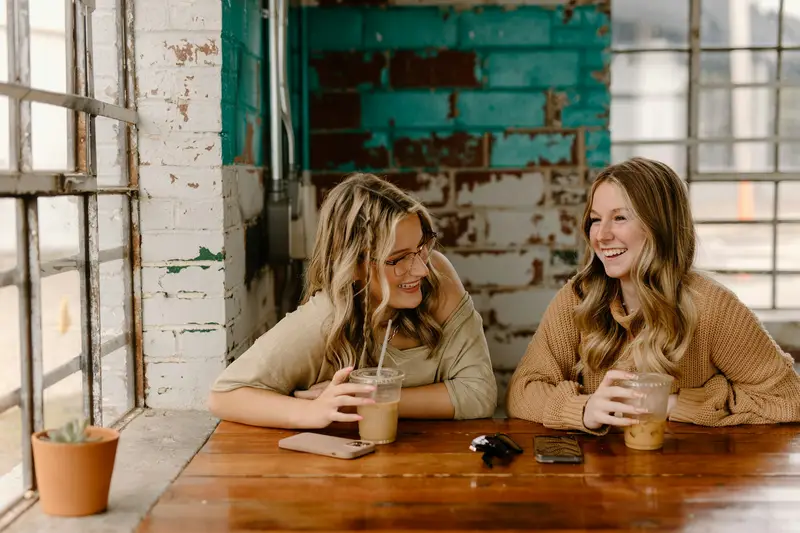 Two friends talking over drinks at a table