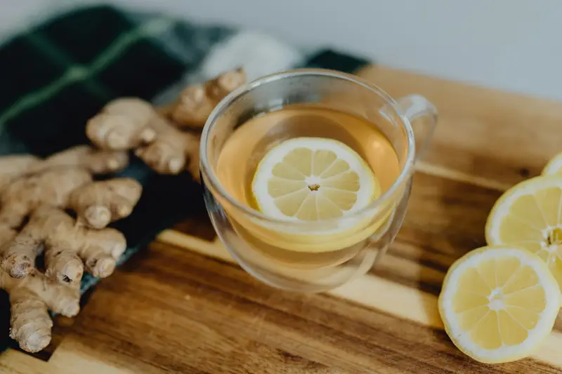 A cup of tea with fresh lemon and ginger on a cutting board