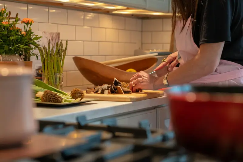 A woman chopping fresh vegetables on a cutting board in a home kitchen