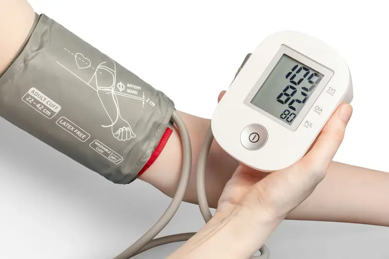 A person checking their blood pressure with a digital monitor and arm cuff