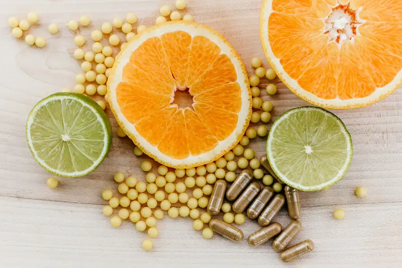 Citrus slices beside vitamin supplement capsules on a wooden surface