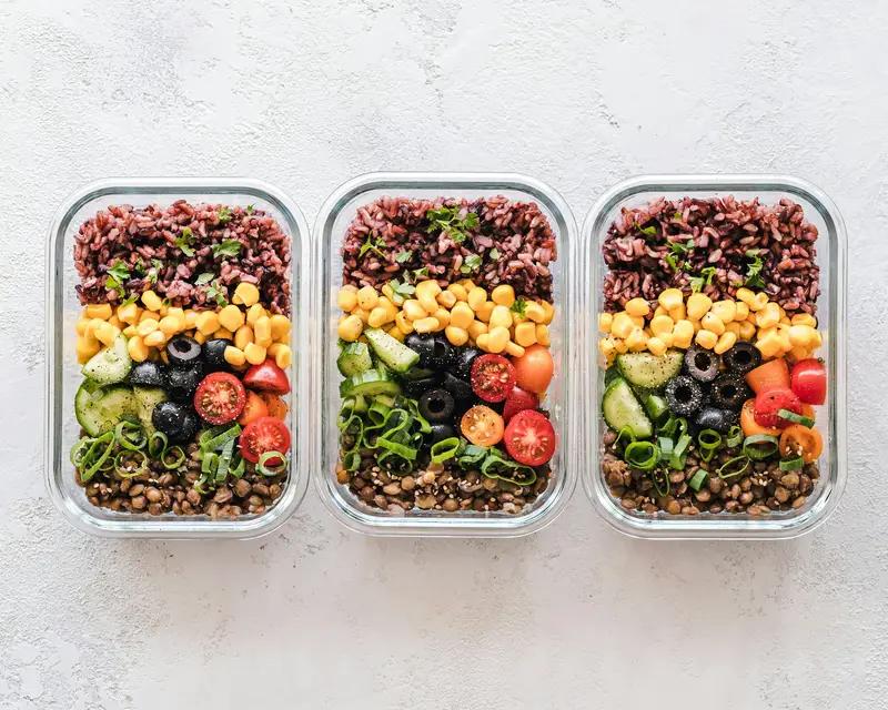 Glass meal-prep containers filled with rice, lentils and vegetables